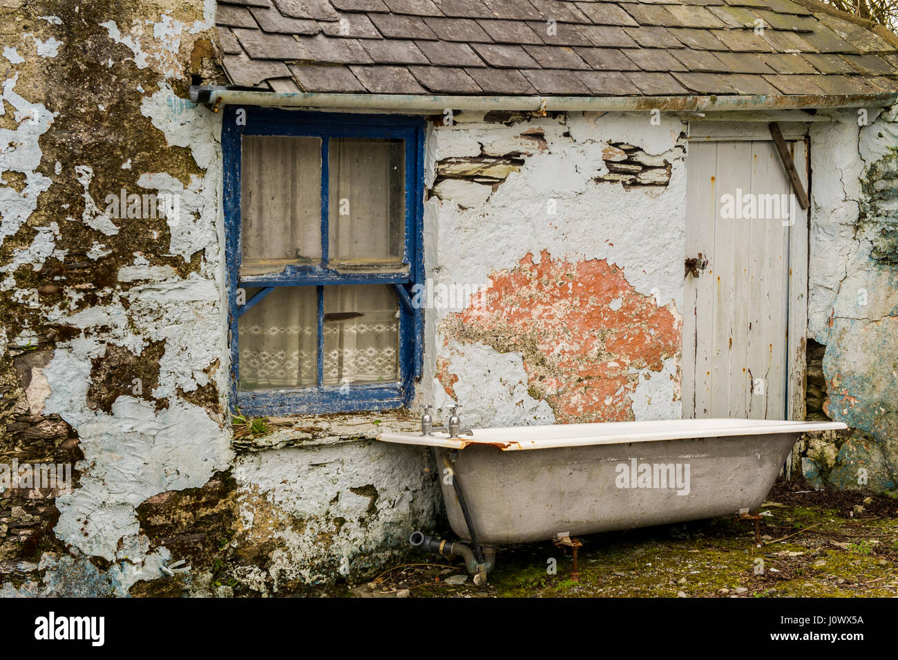 Bath wurde außerhalb eines alten Schuppen mit Fenster und Tür in Schull, Irland, stillgelegt und verlassen. Stockfoto