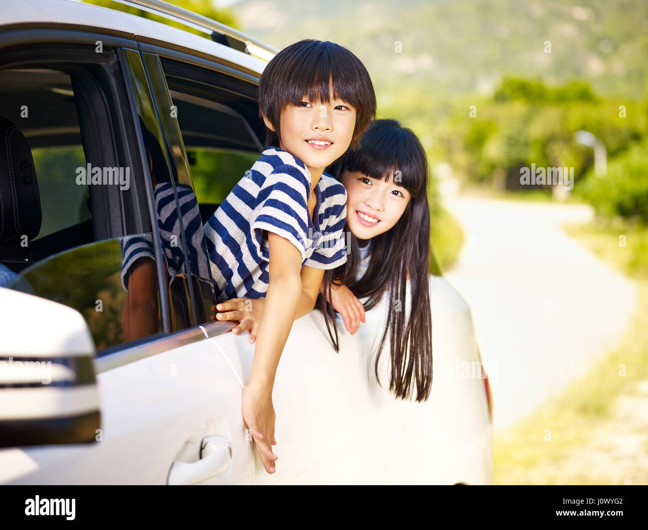 gerne asiatische kleine Jungen und Mädchen stecken ihre Köpfe aus Autofenster Stockfoto