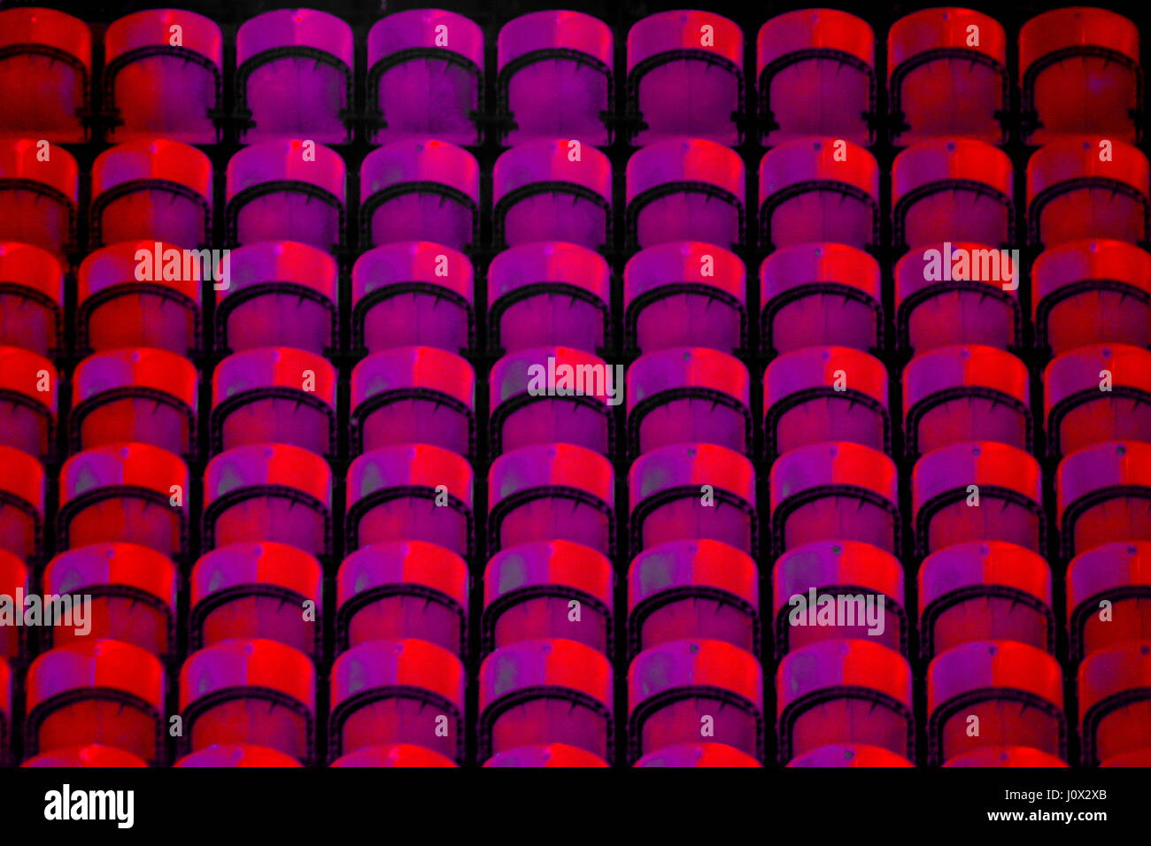 Leere Stadion Tribüne in roten und violetten Farben. Nur Stühle ohne Menschen Stockfoto