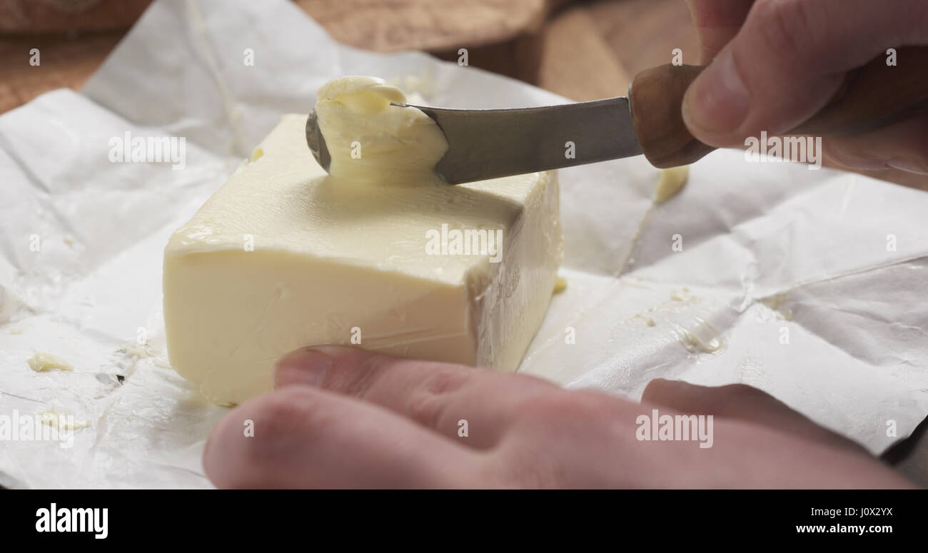 Weibliche Teenager Hände kratzen Butter mit einem Messer Stockfoto