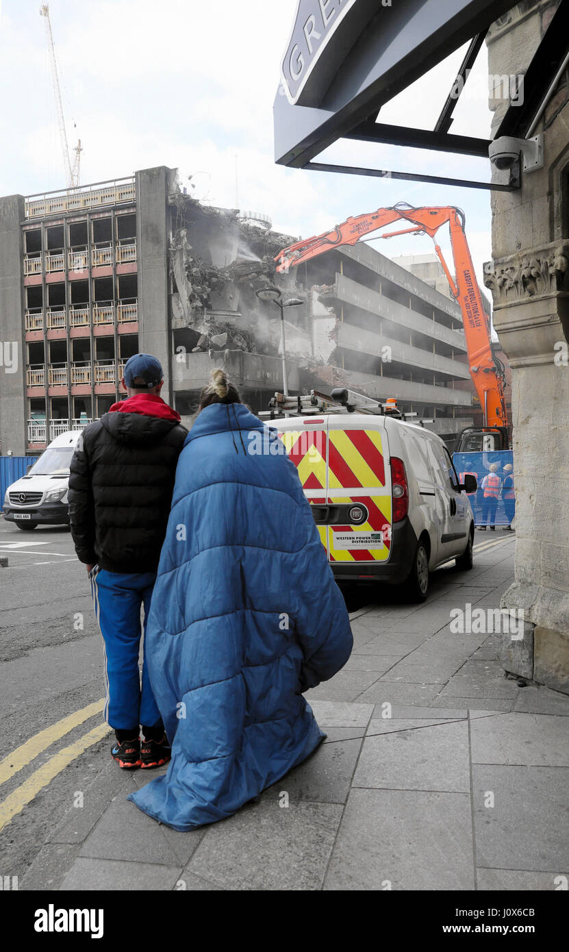 Obdachlosen paar beobachten Spec Bagger Abriss der heruntergekommenen Gebäude auf Baustelle in Wood Street Car Park in Cardiff Wales UK KATHY DEWITT Stockfoto