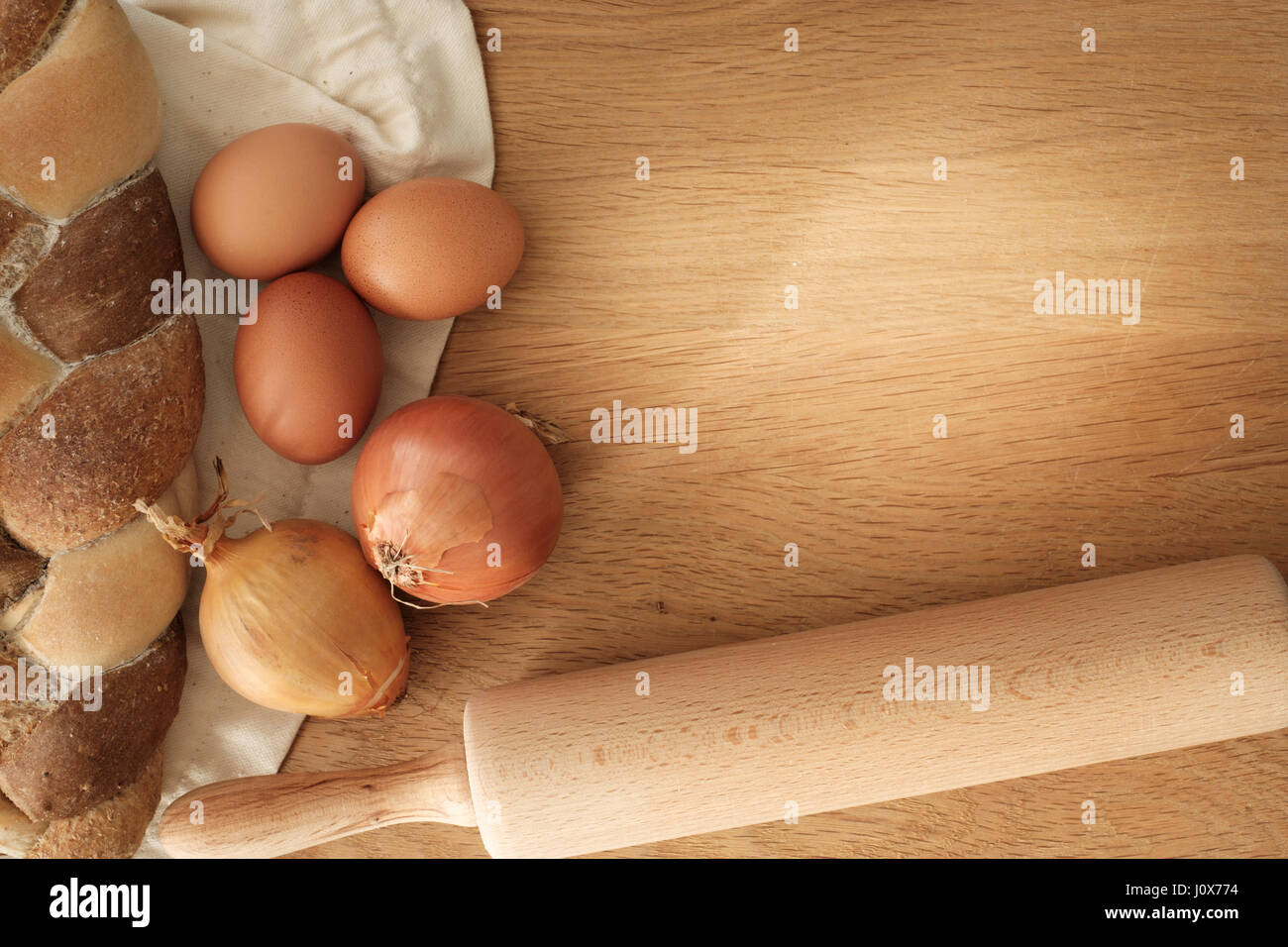 geflochtene Brot mit Zwiebeln, Eiern und Nudelholz auf einem Holztisch mit Textfreiraum, Food-Konzept Stockfoto