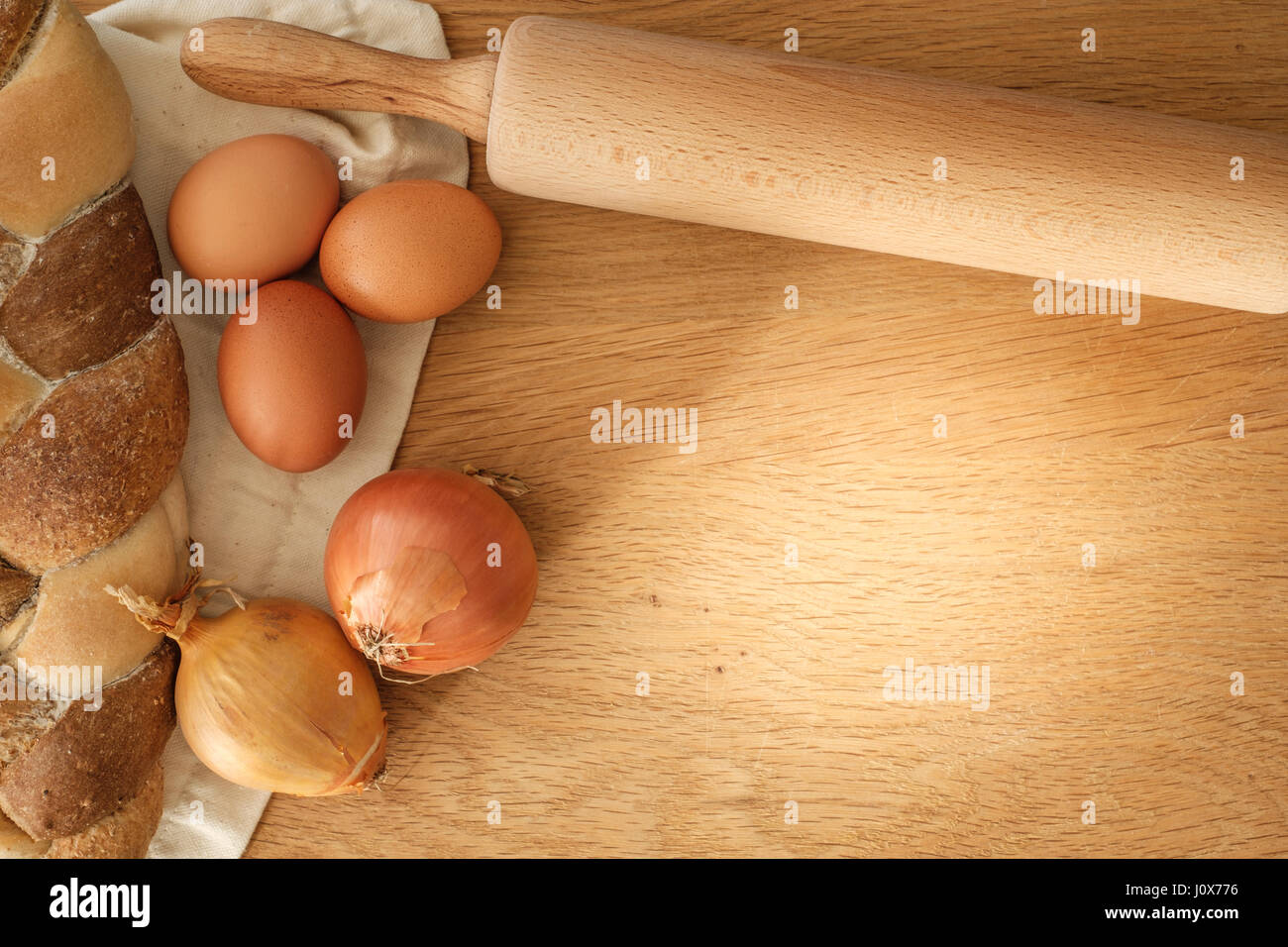 geflochtene Brot mit Zwiebeln, Eiern und Nudelholz auf einem Holztisch mit Textfreiraum, Food-Konzept Stockfoto