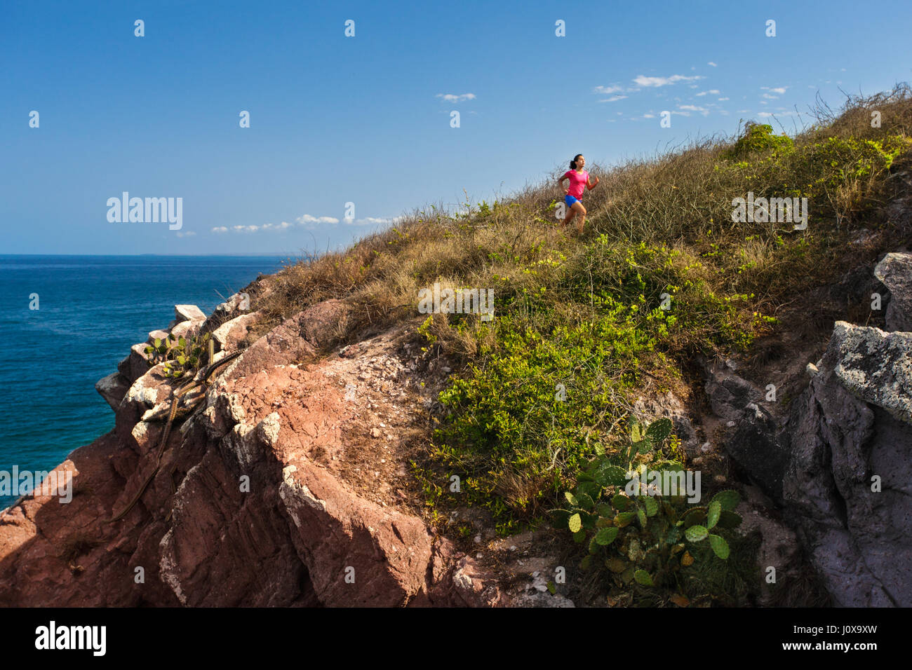 Ein weibliche Läufer joggt auf einem Wanderweg in der Nähe des Ozeans in der Nähe von Mazatlan, Sinaloa, Mexiko. Stockfoto