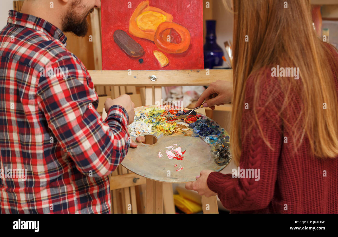 Künstler mit Spachtel und Holzpalette mit Ölfarben erklärt Student Regeln des Zeichnens Ölfarben. Stillleben in der Kunstschule zu schreiben. Kurs Stockfoto