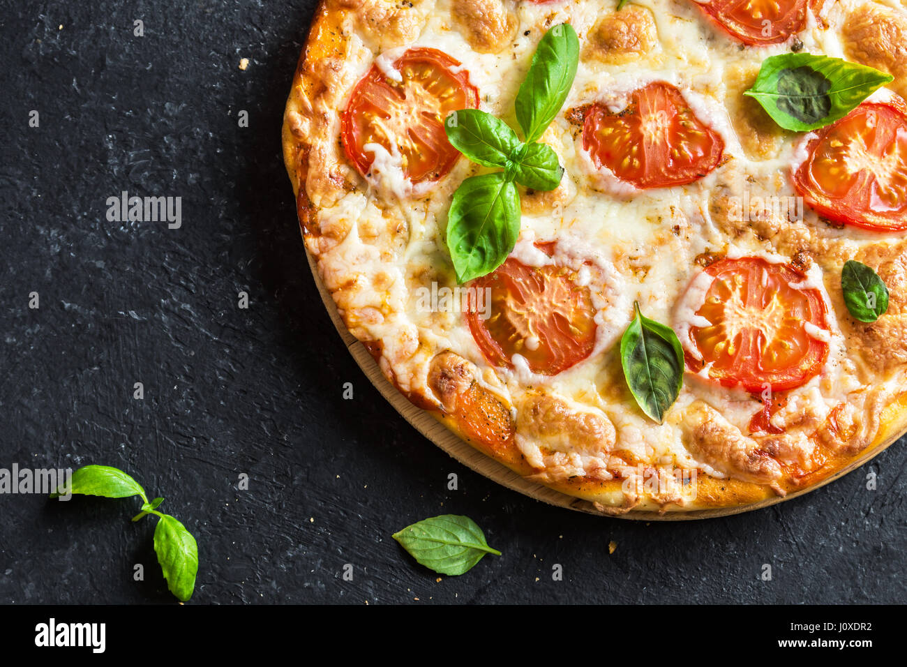 Pizza Margherita auf schwarzem Stein. Pizza Margarita mit Tomaten, Basilikum und Mozzarella-Käse hautnah. Stockfoto