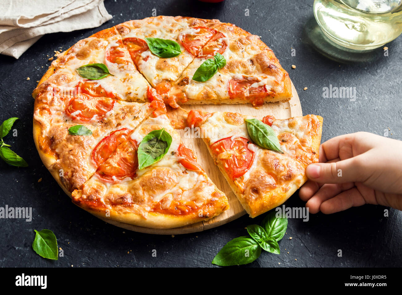 Menschen Hand die Scheibe der Pizza Margherita. Pizza Margarita und Kinderhand hautnah. Stockfoto