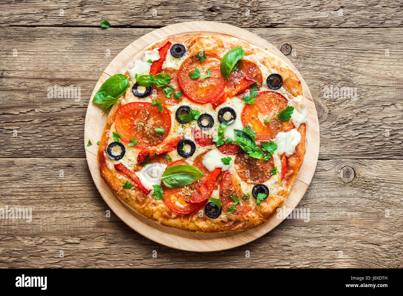 Italienische Pizza mit Tomaten, Salami, schwarzen Oliven und Mozzarella-Käse hautnah. Frische hausgemachte Pizza. Stockfoto