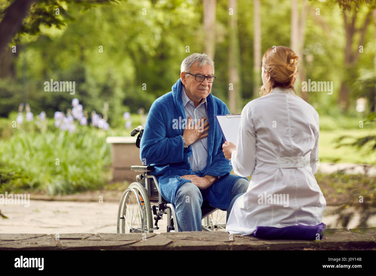 Krankenschwester mit älterer Mann im Rollstuhl, die sich nicht gut fühlen im freien Stockfoto