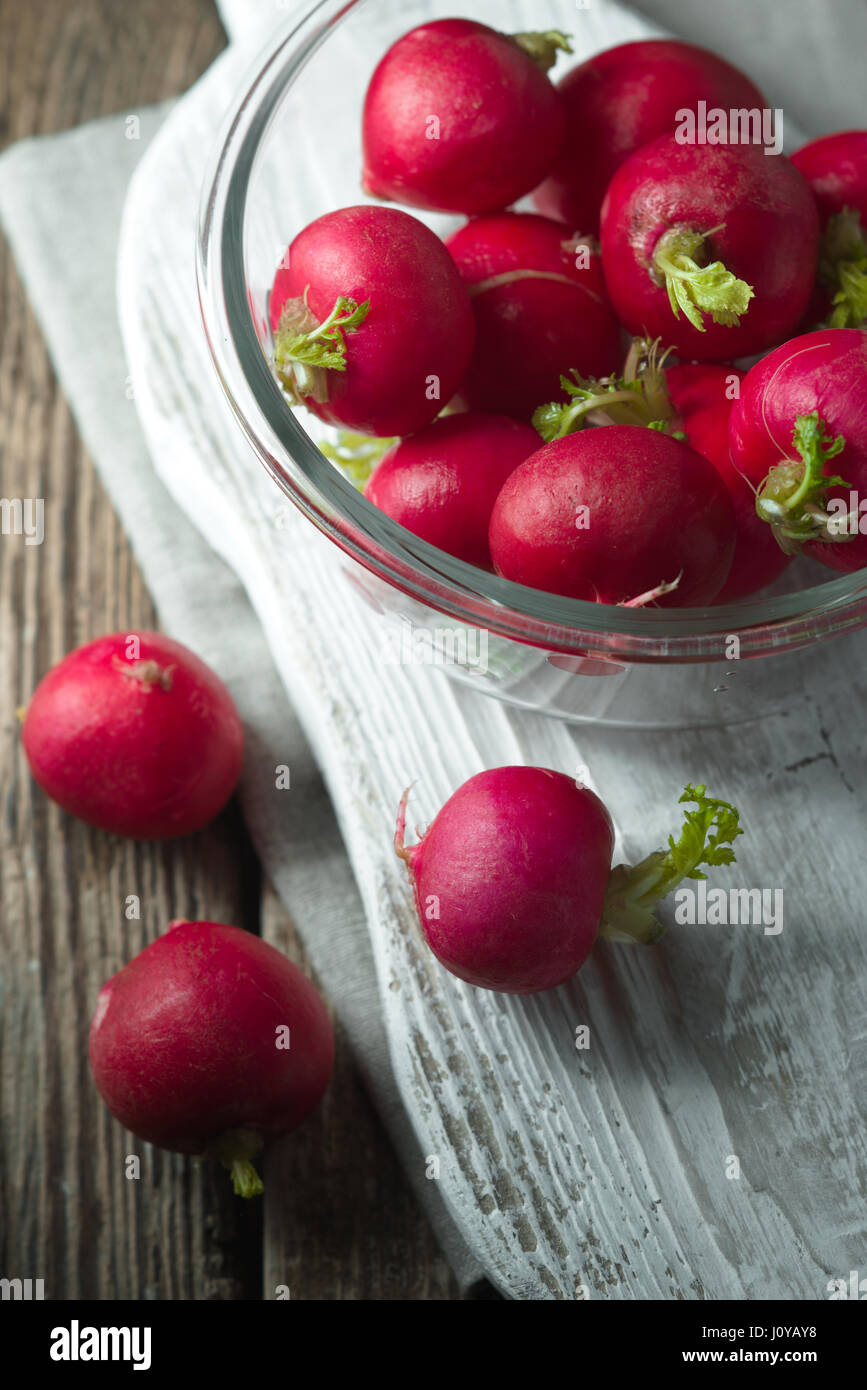 Radieschen in eine Glasschüssel auf einem Holzständer-vertikal Stockfoto