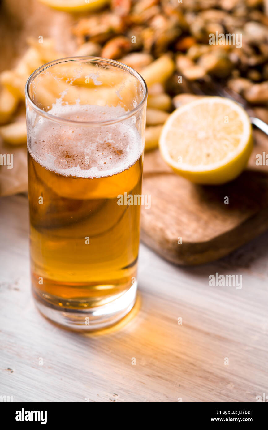 Glas Bier mit unscharfen Snack auf dem weißen Holztisch Stockfoto