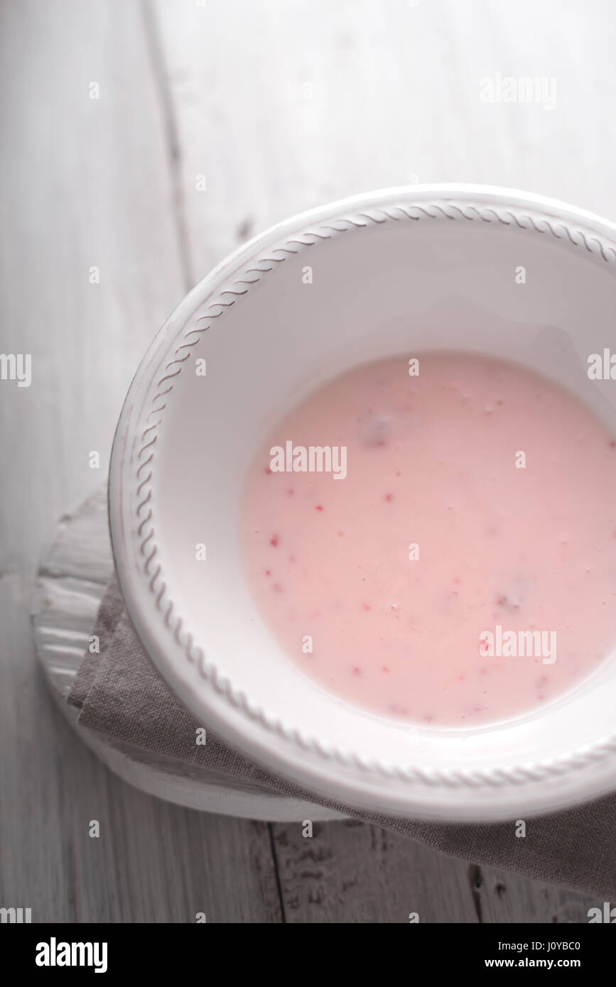 Fruchtjoghurt in die weiße Platte auf dem vertikalen weißen Holztisch Stockfoto