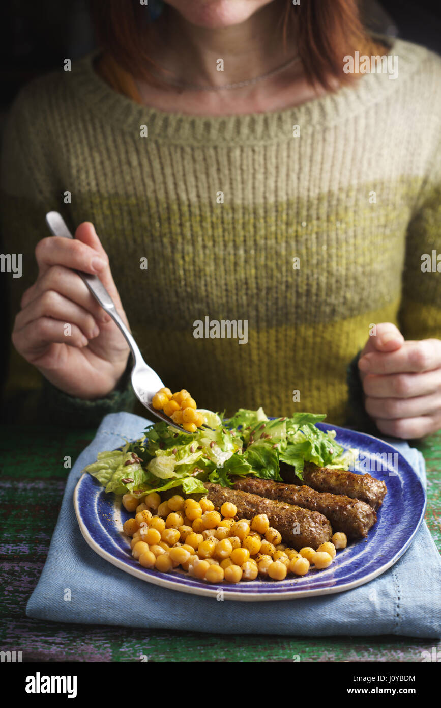 Frau Essen Cevapcici auf dem Holztisch vertikale Stockfoto