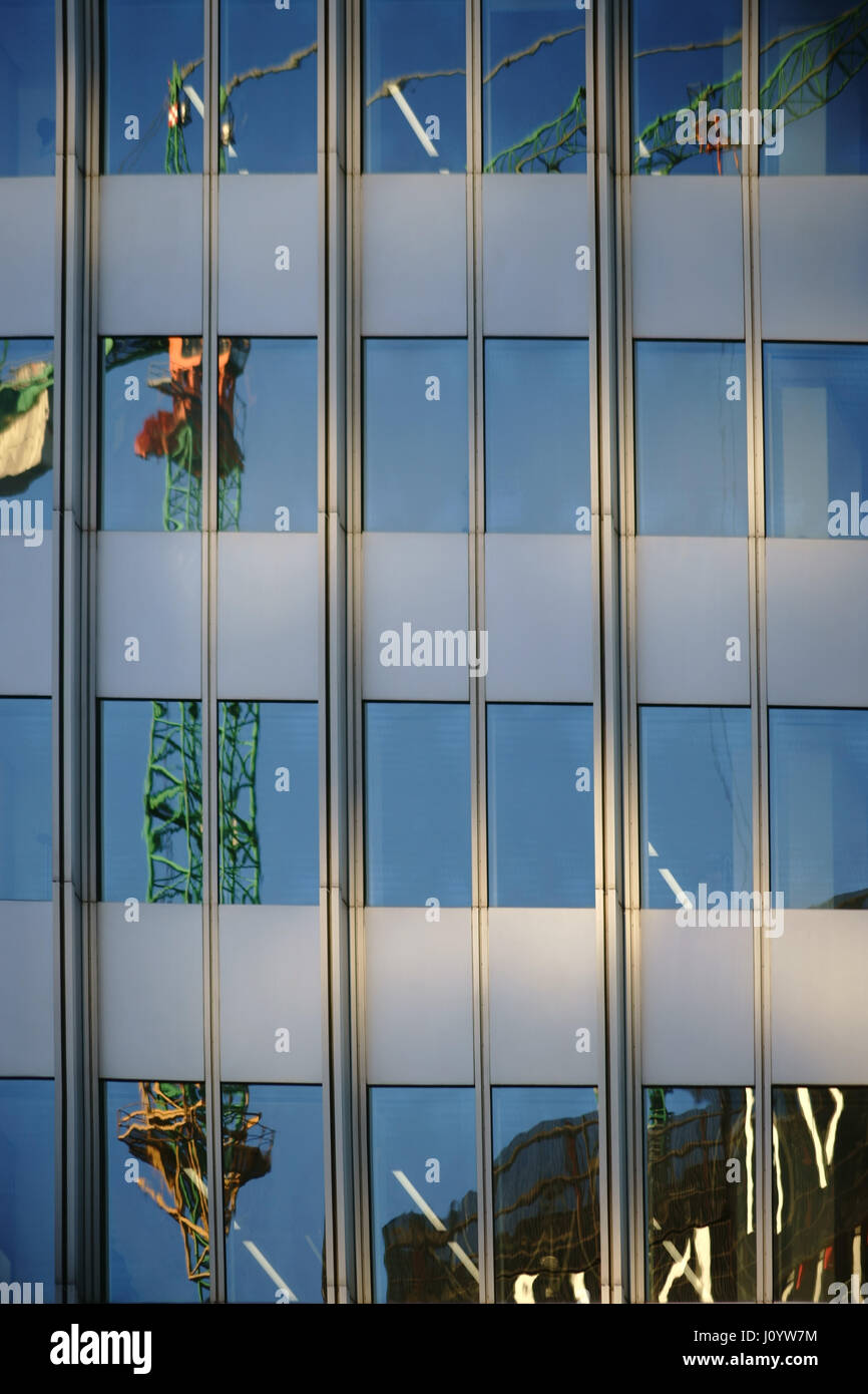 Die unregelmäßige Reflexion eines Krans in eine moderne Fassade der Spiegel Fenster. Stockfoto