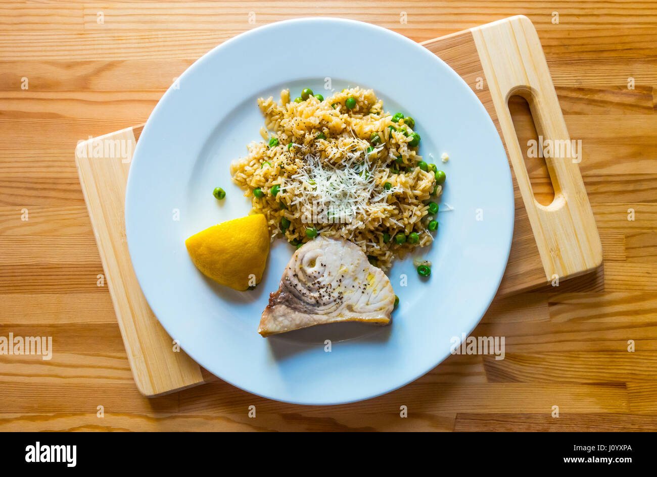 Gegrillter Schwertfisch, brauner Reis, grüne Erbsen mit einer Zitronenscheibe Stockfoto