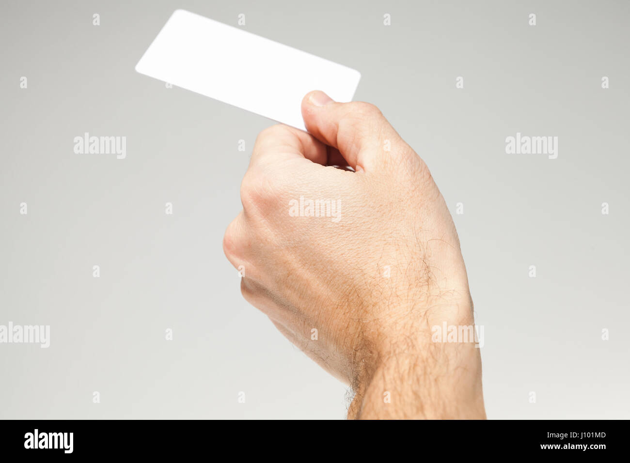 Männliche Hand hält weiße Karte über grauen Hintergrund, Nahaufnahme Foto, selektiven Fokus Stockfoto