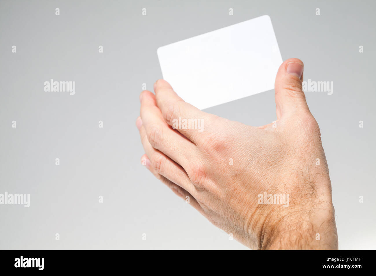 Männliche Hand hält weiße leere Karte über grauen Hintergrund, Nahaufnahme Foto, selektiven Fokus Stockfoto