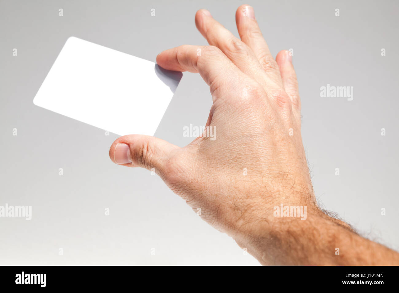 Männliche Hand hält weiße leere Karte über grauen Hintergrund, Nahaufnahme Foto, selektiven Fokus Stockfoto