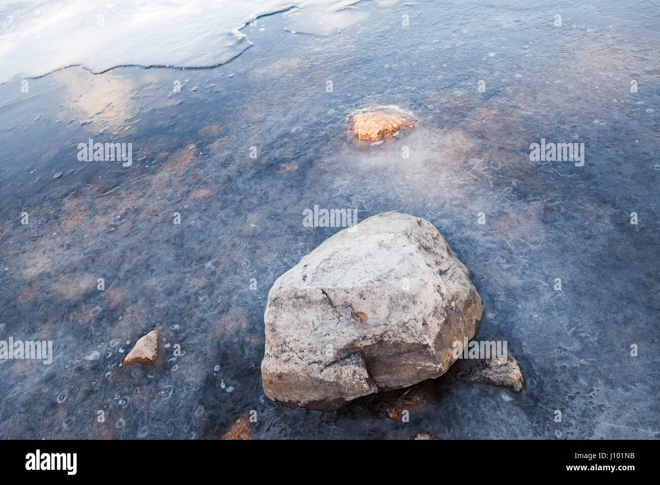 Stein liegt am Saimaa-See Küste mit Eis bedeckt Stockfoto