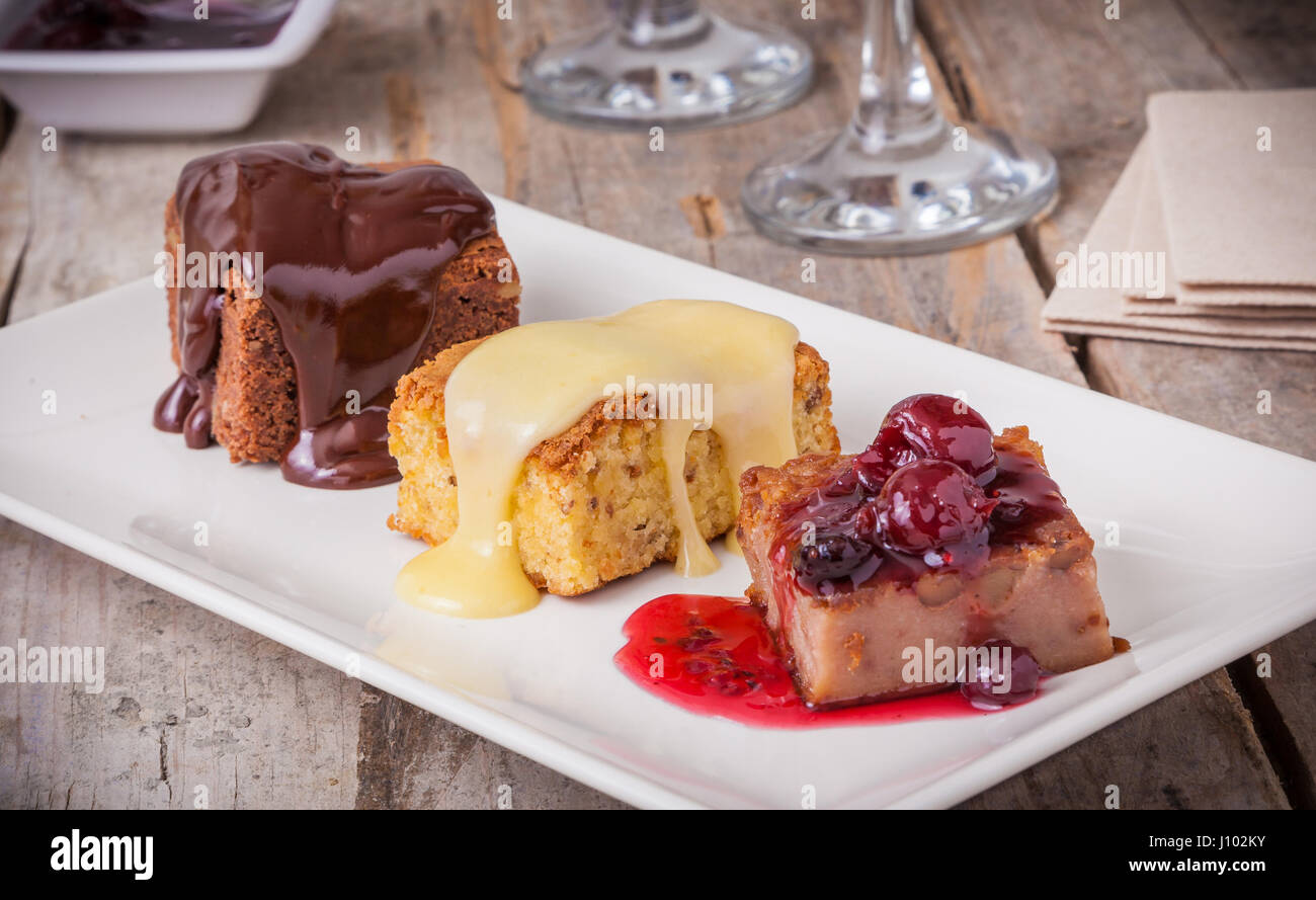 Drei verschiedene Desserts: Kuchen mit Schokolade, Vanille-Kuchen und Kirsch-Pudding mit Soße. Stockfoto