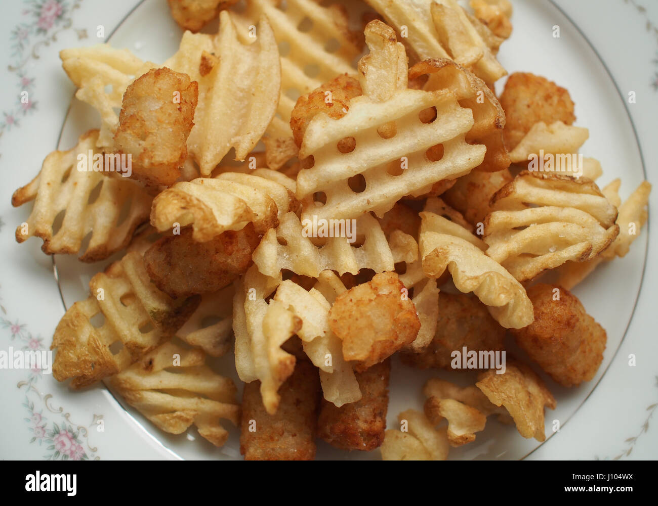 Kohlenhydrat-Überladung: ein Teller voll mit Waffel Pommes Frites und Tater Tots Stockfoto