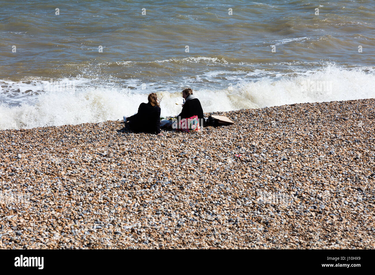 Deal, Kent, England, Vereinigtes Königreich, 17. April 2017. Ein beschäftigt Ostern Feiertag genießen Sie Montag am Strand von Deal UK am Ärmelkanal trotz der kalten Winden, zwei Frauen Essen neben den tosenden Wellen, Richard Donovan/Alamy Live News Stockfoto