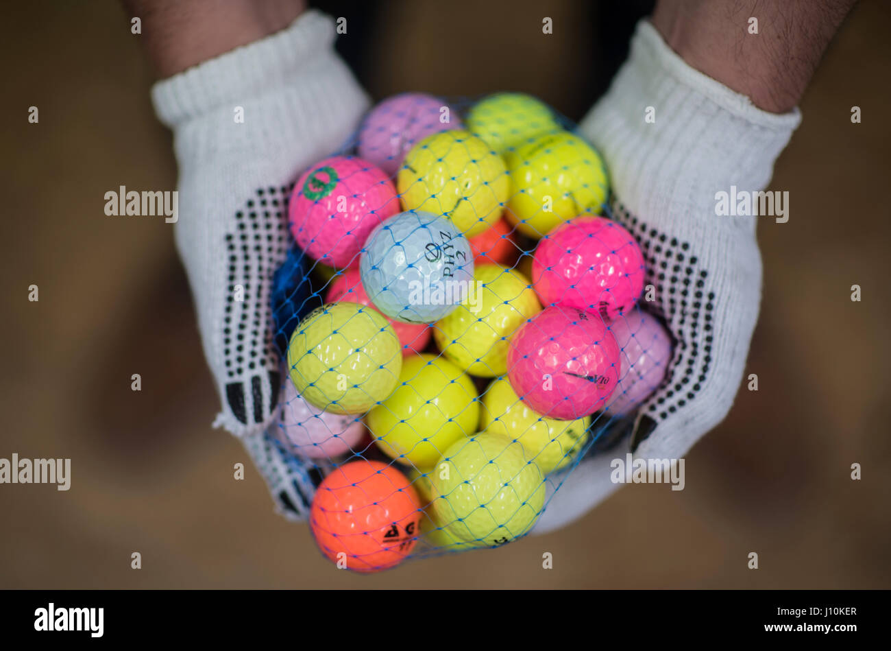 Wiesbaden, Geramny. 11. April 2017. Zwei Hände halten ein Netz mit gebrauchte Golfbälle, eine so genannte "Marke Mischung", in Wiesbaden, Geramny, 11. April 2017. Das Unternehmen "Easy-Lakeballs" ist spezialisiert auf das recycling von Golfbällen. Die Kunden sichere rund 50 Prozent des Einzelhandel-Preises. Foto: Andreas Arnold/Dpa/Alamy Live-Nachrichten Stockfoto