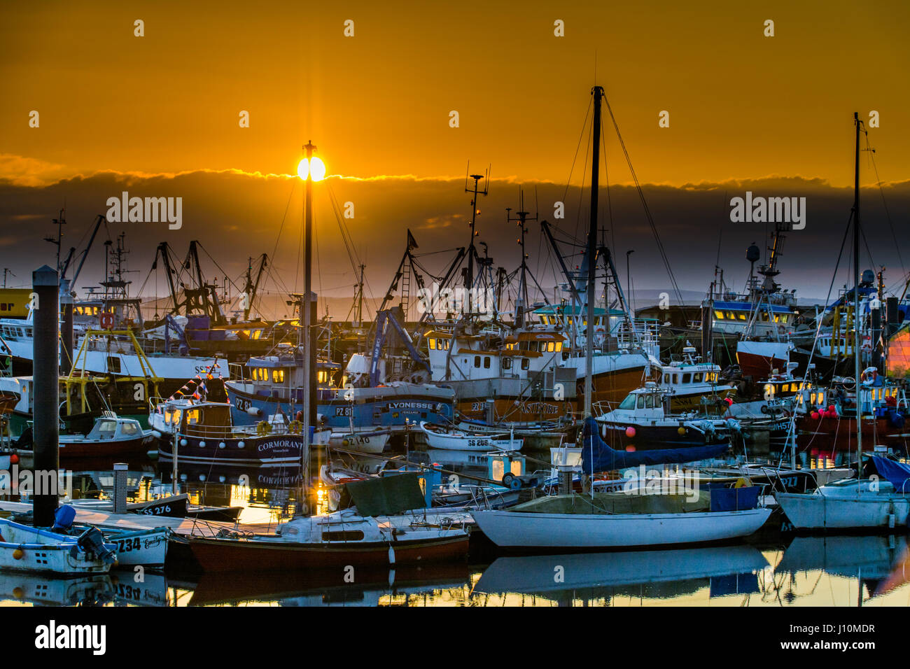 Newlyn, Cornwall, UK. 18. April 2017. Großbritannien Wetter. Die Sonne geht über eine Bande von niedrigen Wolken in Newlyn Harbour.  Die Prognose für den Rest der Woche ist für viel Sonnenschein - für die meisten Menschen die Osterferien sind nun vorbei. Bildnachweis: Simon Maycock/Alamy Live-Nachrichten Stockfoto