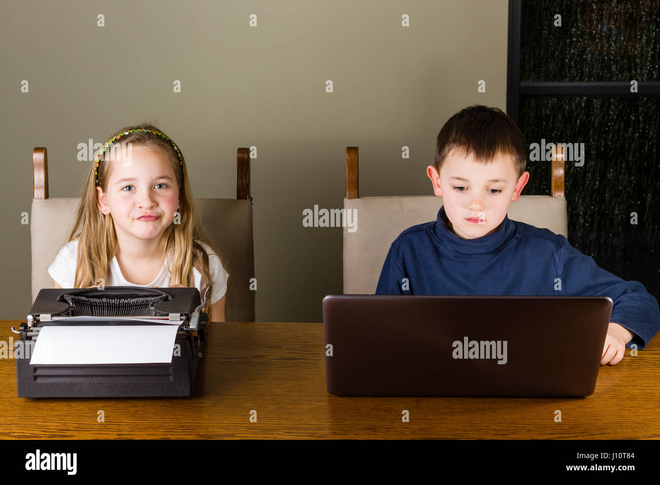 jungen und Mädchen arbeiten auf alten Schreibmaschine und laptop Stockfoto