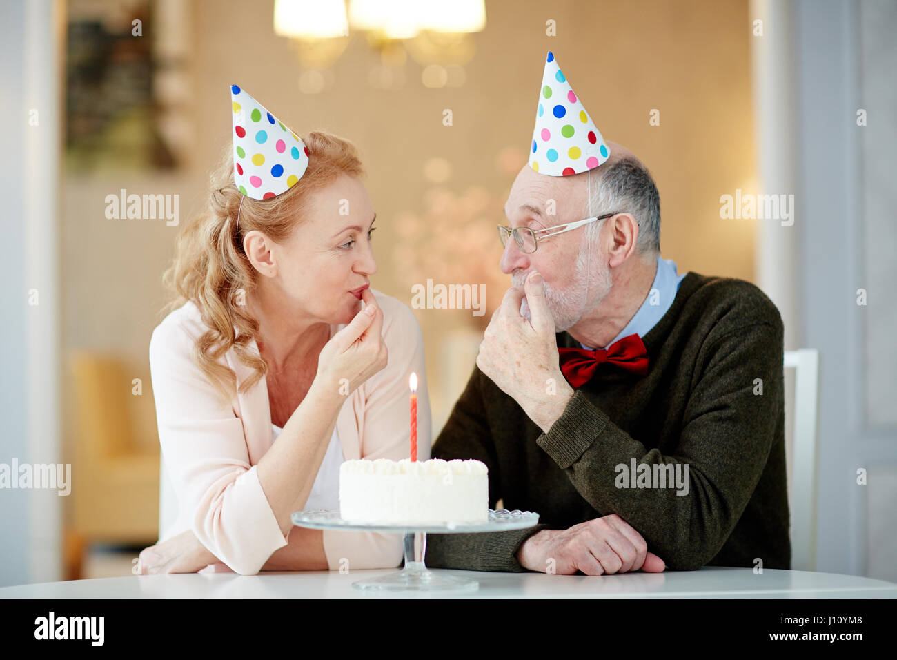 Reifer Mann und Frau in Geburtstag Kappen schmecken lecker dessert Stockfoto