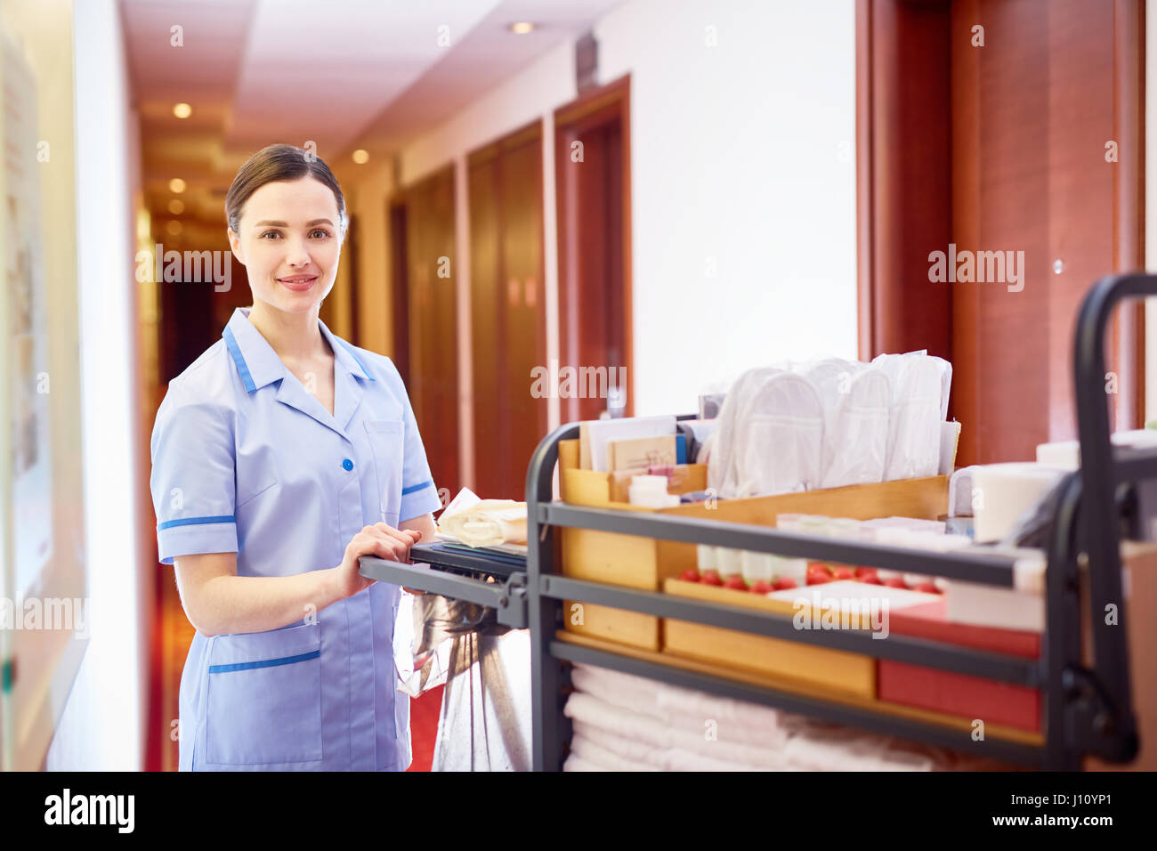 Hausmädchen, Schieben Karren mit sauberer Bettwäsche während des Gehens auf Flur des Hotels Stockfoto