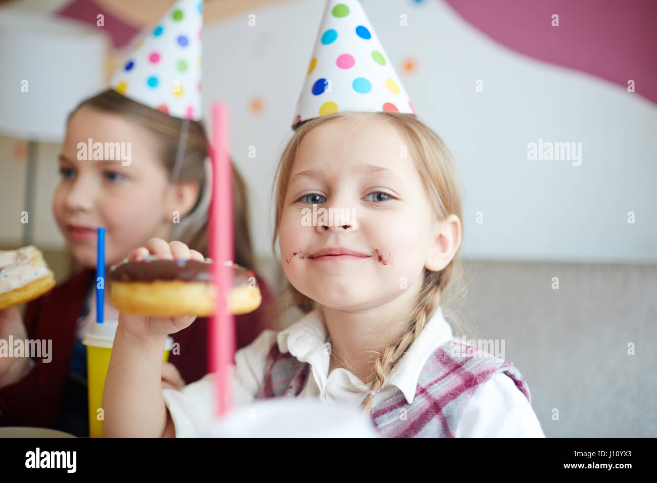 Kleines Mädchen mit Donut genießen-Geburtstags-party Stockfoto