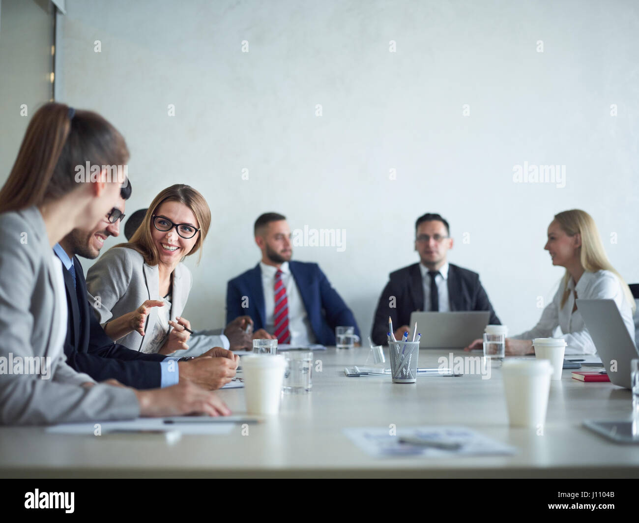 Gruppe von fröhlichen Geschäftsleute Lächeln auf den Lippen und im Chat am Besprechungstisch im Konferenzraum Stockfoto