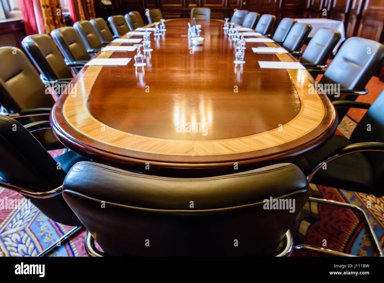 Großer Holztisch in einen Sitzungssaal mit Holz Verkleidung, eingerichtet für ein Treffen Stockfoto
