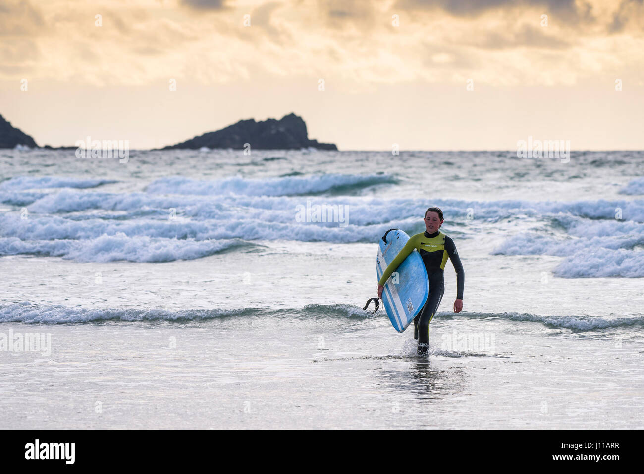 Surfen-UK; Surfer; Fistral; Cornwall; Fuß aus dem Meer; Surfbrett tragen; Meer; Watersport; Am Abend; Müde; Freizeitbeschäftigung; Lebensstil Stockfoto