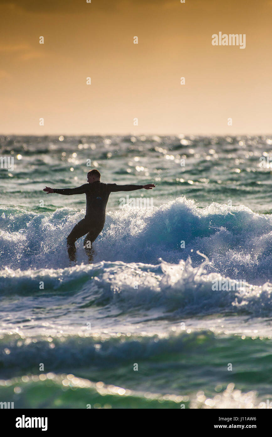 Surfen UK Surfer Fistral Cornwall Wave Surf Board Sea Spray Wassersport Abend Sonnenuntergang körperliche Aktivität können spektakuläre action Stockfoto