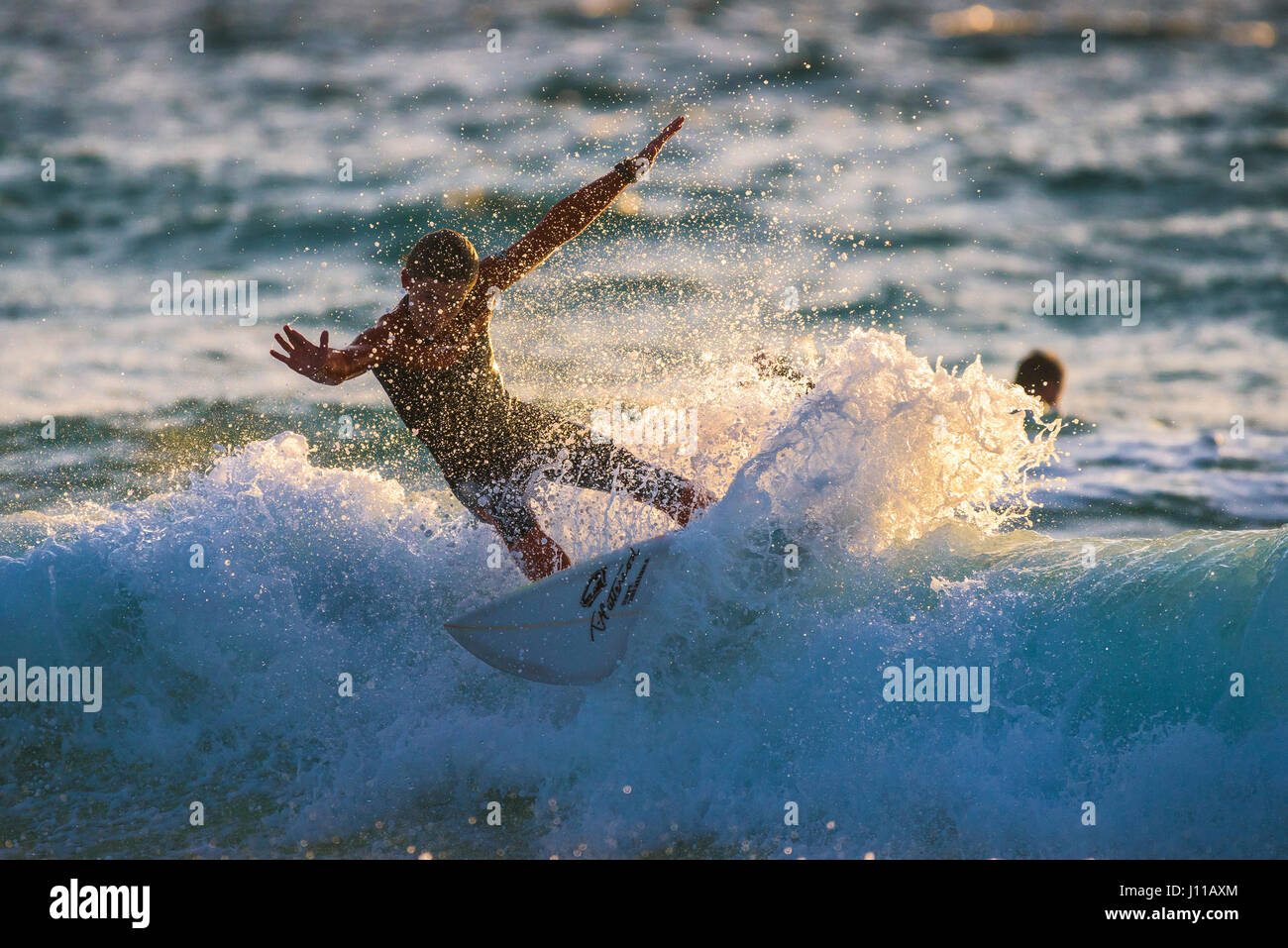 UK Surfer Sonnenuntergang Spray Wasser Fistral Cornwall Abendlicht Wave Surf Board Meer Wassersport Abend körperliche Aktivität Skill Surfen Stockfoto