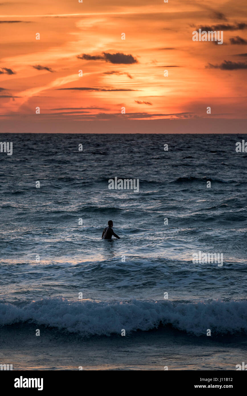 Surfen-UK. Ein Surfer warten auf eine Welle bei Sonnenuntergang, Fistral Strand, Newquay, Cornwall. Stockfoto