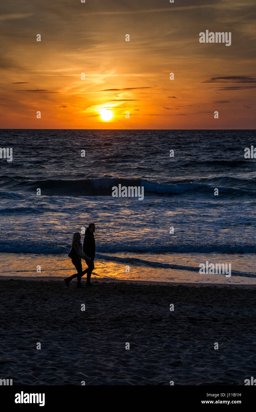 Intensive Sonnenuntergang; Meer; Meer; Paar; Menschen in Silhouette; Wandern entlang der Küste; Abend; Ende des Tages; Romantisch; Fistreal; Newquay Stockfoto