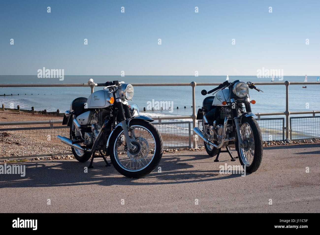 Zwei Royal Enfield Bullet Motorräder parken vor dem Strand in Großbritannien Stockfoto