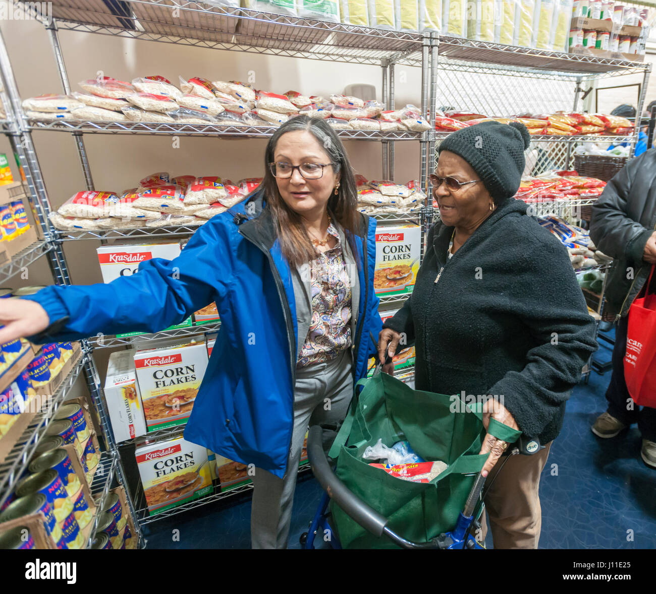 Ein Client, Recht, wird bei der Auswahl Essen im katholischen Wohltätigkeitsorganisationen Bronx Food Distribution Center in New York am Heiligen Donnerstag, 13. April 2017 unterstützt. Das Verteilzentrum, ausgestattet mit großzügigen Spenden von Goya Foods und andere Unternehmen Prozesse 513.000 Pfund Essen pro Monat verteilen direkt an die Bedürftigen und über ein Netz von interreligiösen Essen Vorratskammern in der Bronx und Upper Manhattan. Katholischen Wohltätigkeitsorganisationen feiert dieses Jahr sein 100-Jahr-Jubiläum. (© Richard B. Levine) Stockfoto