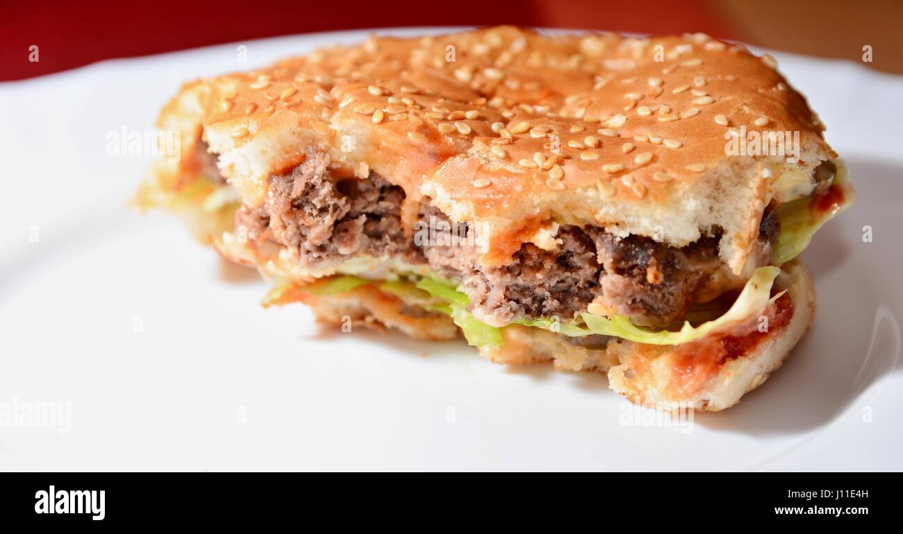 Nahaufnahme der hausgemachte ordentlichen Hamburger mit einem Bissen fehlt. Typische ungesunde Lebensmittel. Stockfoto