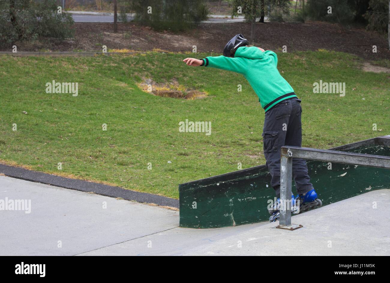 Junge Teenager wackeln auf Inline-Skates eine Rampe hinunter. Stockfoto