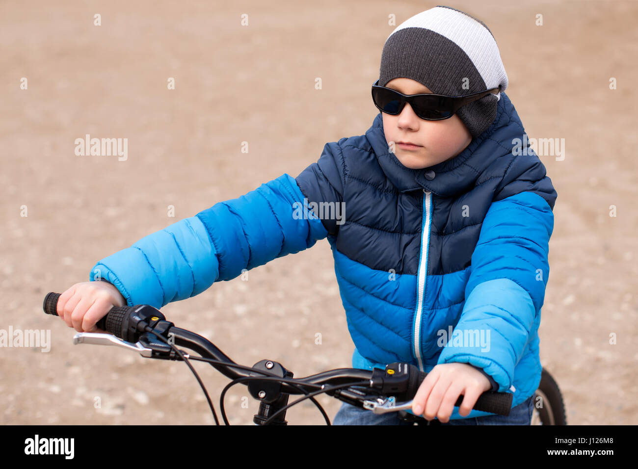 Ein Junge mit Sonnenbrille sitzt auf einem Fahrrad. Stockfoto