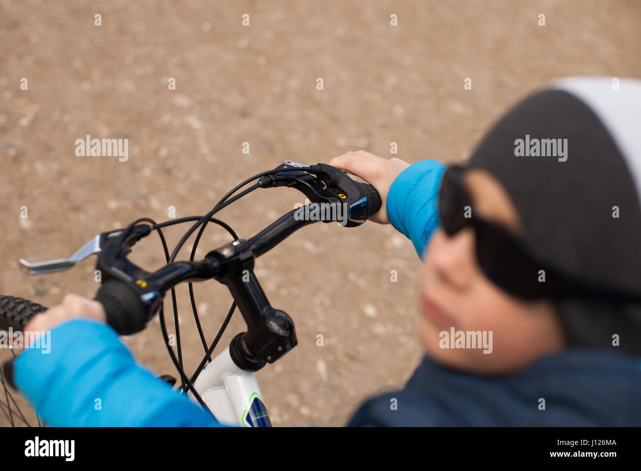 Ein Junge mit Sonnenbrille sitzt auf einem Fahrrad. Stockfoto