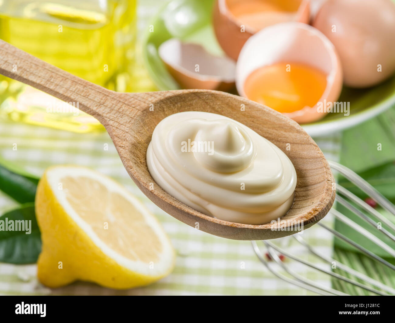 Natürliche Mayonnaise Soße in den Kochlöffel und die Zutat auf dem Hintergrund. Stockfoto