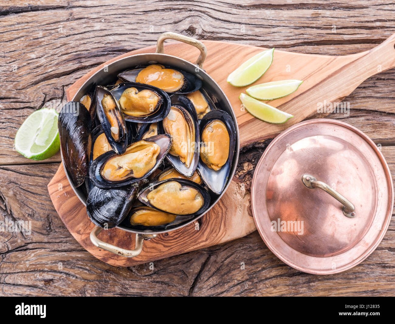 Gekochte Muscheln in Kupfer Pfanne auf dem Holztisch. Stockfoto