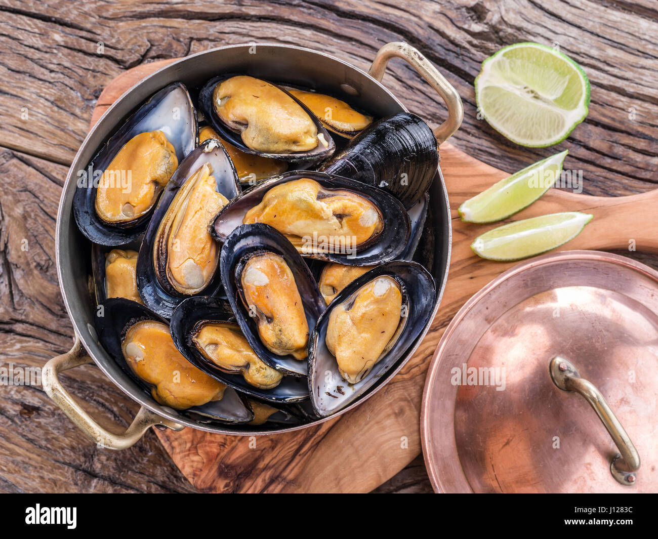 Gekochte Muscheln in Kupfer Pfanne auf dem Holztisch. Stockfoto