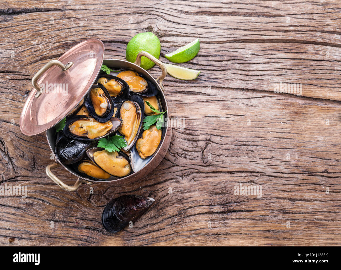 Gekochte Muscheln in Kupfer Pfanne auf dem Holztisch. Stockfoto