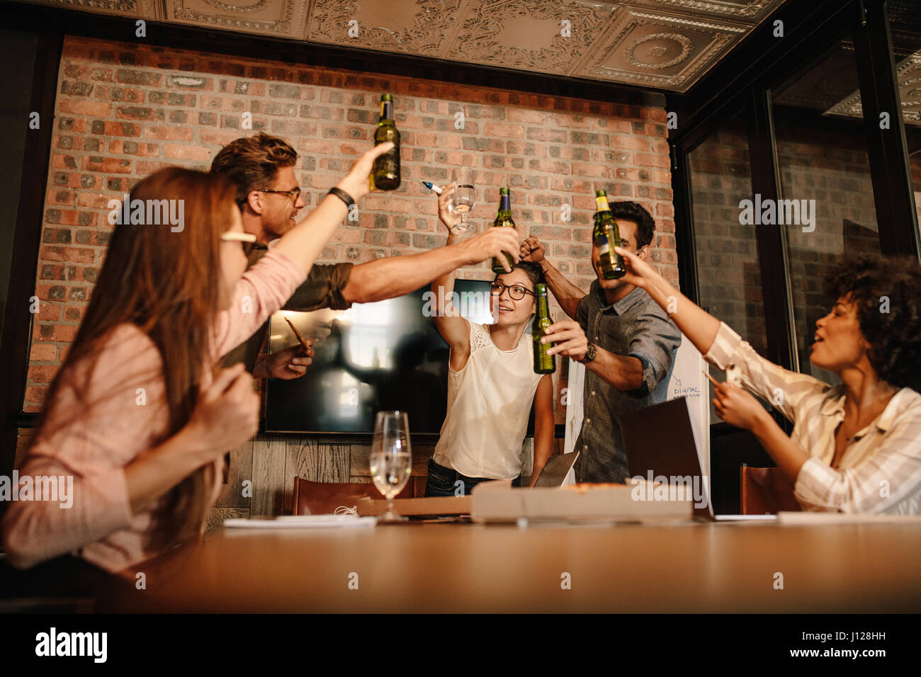 Gruppe von erfolgreichen jungen Geschäftsleute mit Bier zu feiern. Heterogene Gruppe von Menschen, die Getränke über erfolgreichen Geschäftsabschluss. Stockfoto